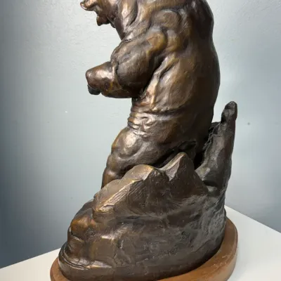 Sale Photo Thumbnail #127: Western-style bronze sculpture depicting a rearing bear on a rocky outcrop, mounted on an oval wooden base.