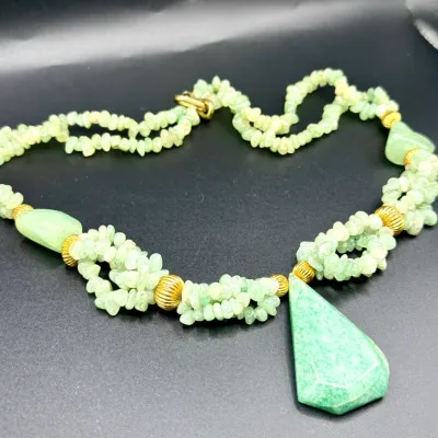 Sale Photo Thumbnail #342: Multi-strand light green gemstone chip necklace featuring ribbed gold-tone spacer beads and a large faceted teardrop pendant.