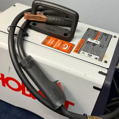 Sale Photo Thumbnail #501: Hobart portable arc welder unit with attached cables, ground clamp, and MIG gun torch attachment.