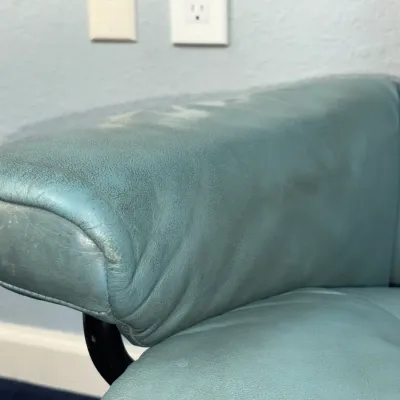 Sale Photo Thumbnail #227: Close-up of a teal leather armchair armrest showing moderate surface wear and light scuffing.