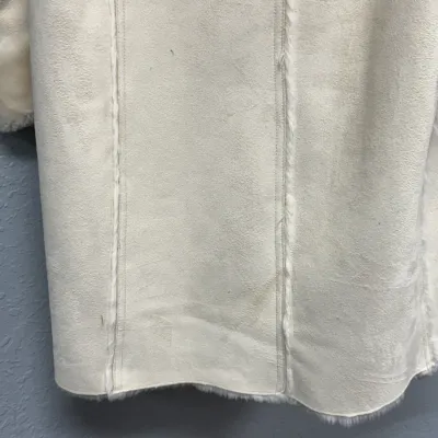 Sale Photo Thumbnail #856: Close-up of a off-white faux suede and shearling coat showing vertical seam details and minor surface wear.