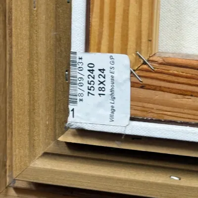 Sale Photo Thumbnail #834: Detail view of the back of a framed painting canvas with an identification tag reading "Village Lighthouse ES G/P 18X24".
