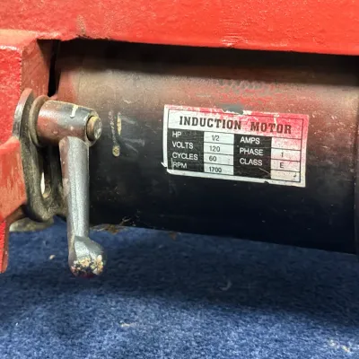 Sale Photo Thumbnail #556: Detail view of a vintage power tool's 1/2 HP induction motor, showing the specifications label and tension release lever.