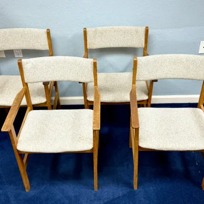 Sale Photo Thumbnail #690: Set of four mid-century modern wooden armchairs featuring beige textured fabric upholstery and exposed wood frames.