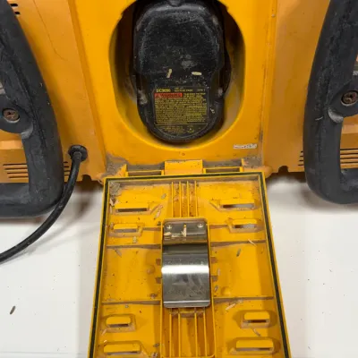 Sale Photo Thumbnail #912: DeWalt jobsite radio charger compartment with a DC9096 18V battery pack installed, showing signs of heavy workshop use.