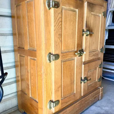 Sale Photo Thumbnail #267: Antique oak icebox cabinet featuring paneled doors and heavy brass hardware, showing light surface wear consistent with age.