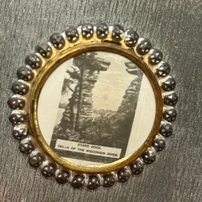 Sale Photo Thumbnail #198: Vintage circular souvenir pin featuring a black-and-white photograph of Stand Rock at Dells of the Wisconsin River, framed by a beaded metal border.