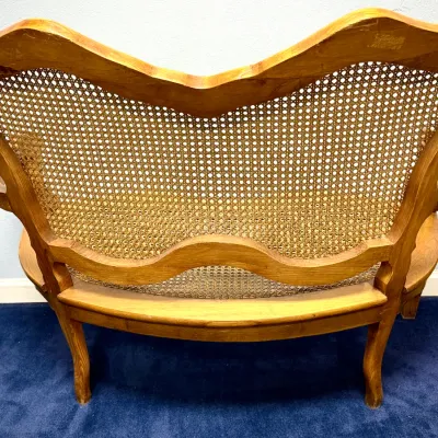 Sale Photo Thumbnail #678: French Provincial style light wood settees featuring a double-seat design with woven cane backrests and cabriole legs.