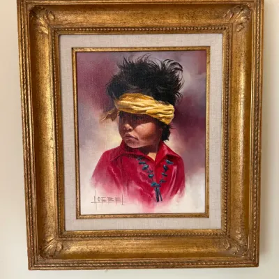 Sale Photo Thumbnail #146: Framed oil painting portrait of a young Native American child wearing a yellow headband and red shirt, signed by the artist in the lower left corner and set in a gilded ornate frame.