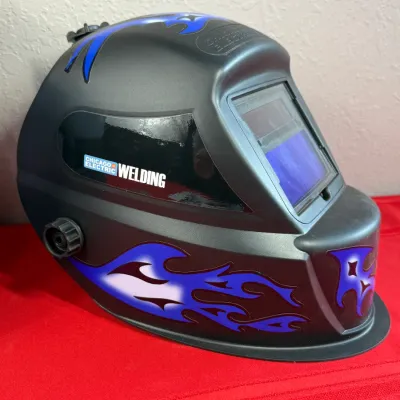 Sale Photo Thumbnail #524: Chicago Electric Welding auto-darkening welding helmet featuring black shell with blue flame graphics in clean, lightly used condition.