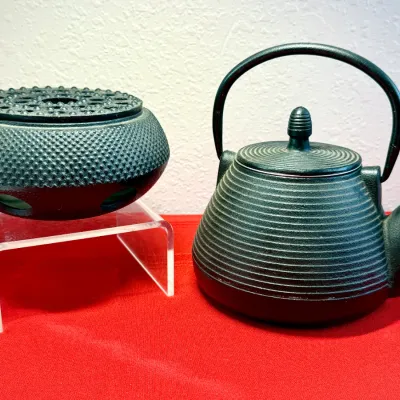 Sale Photo Thumbnail #36: Dark green cast iron Japanese tetsubin teapot with a ribbed body alongside a matching hobnail-textured teapot warmer.