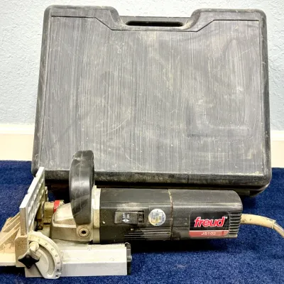 Sale Photo Thumbnail #55: Freud model JS102 biscuit joiner, showing light surface dust and wear, complete with its original molded plastic hardshell carrying case.