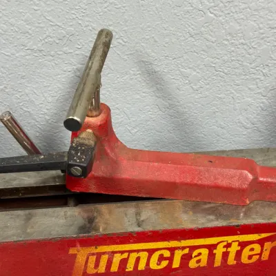 Sale Photo Thumbnail #557: Turncrafter wood lathe tool rest and base assembly mounted on the lathe bed, showing light signs of use.