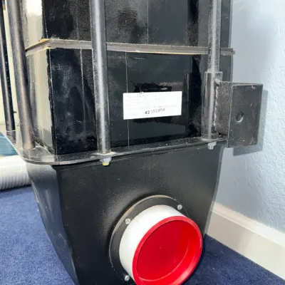 Sale Photo Thumbnail #539: Black industrial-style air intake or filter assembly with a red cap on the lower outlet port, featuring a metallic frame and serial label.
