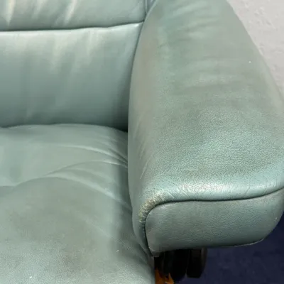 Sale Photo Thumbnail #226: Close-up of a light blue leather Stressless-style recliner chair showing wear and scuffing on the armrest.