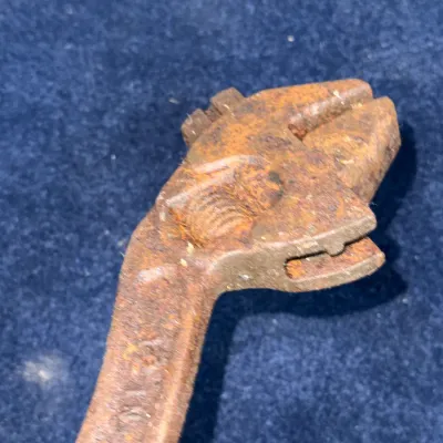 Sale Photo Thumbnail #564: Vintage heavily rusted cast iron adjustable wrench, displaying heavy surface patina and age-related wear.