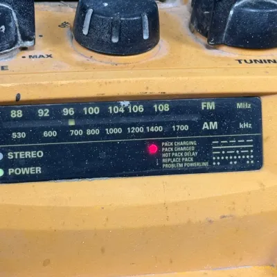 Sale Photo Thumbnail #909: DeWalt rugged jobsite radio charger with AM/FM tuner display and control knobs, showing light surface dust and wear.