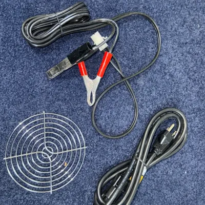 Sale Photo Thumbnail #548: Collection of electrical accessories, including a three-prong AC power cord, a wire lead set with red and black alligator clips, and a circular metal wire fan guard grate.