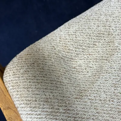 Sale Photo Thumbnail #700: Close-up detail of beige textured herringbone woven upholstery fabric on a wooden chair frame.