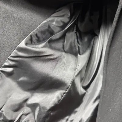 Sale Photo Thumbnail #861: Close-up view of the smooth black satin interior lining of a heavy wool jacket or coat.