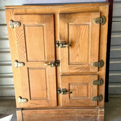 Sale Photo Thumbnail #264: Antique oak icebox cabinet featuring three paneled doors and original brass hardware, circa early 20th century.