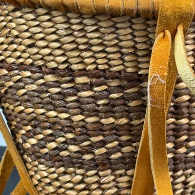 Sale Photo Thumbnail #407: Handwoven twined basket with dark contrast banding, featuring buckskin suede trim wrapped along the rim and long leather straps.