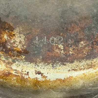 Sale Photo Thumbnail #586: Close-up detail of a vintage cast iron cookware bottom displaying stamped patent numbers and the mold mark 1402 A.
