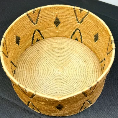 Sale Photo Thumbnail #382: Handwoven cylindrical basket featuring dark geometric diamond and arrow patterns along the interior and exterior walls.