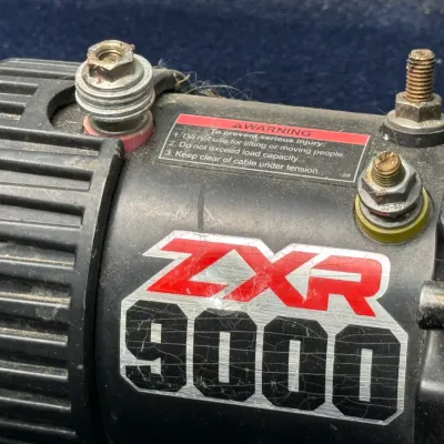 Sale Photo Thumbnail #663: Badland ZXR 9000-lb electric winch motor displaying branding and electrical terminal connections.