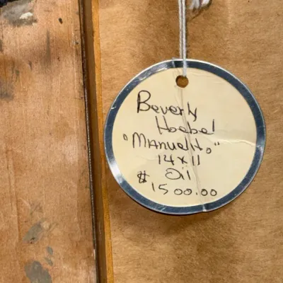 Sale Photo Thumbnail #144: Paper estate sale tag detailing artist Beverly Hoebel's oil painting titled 'Manuelito' measuring 14x11 inches.