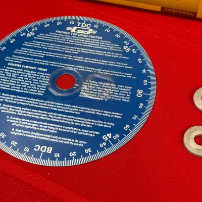 Sale Photo Thumbnail #536: Vintage Mr. Gasket Co. blue aluminum engine degree wheel with two metal spacers on a red surface.
