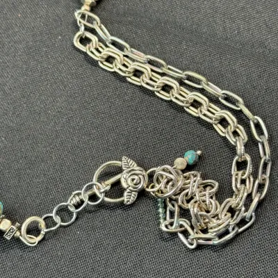 Sale Photo Thumbnail #341: Handcrafted multi-strand silver-tone chain necklace featuring gemstone beads including turquoise and lapis, finished with a decorative floral toggle clasp.