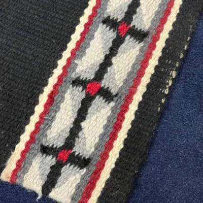 Sale Photo Thumbnail #438: Detail view of a hand-woven wool textile featuring a geometric Southwestern design in black, grey, white, and red.