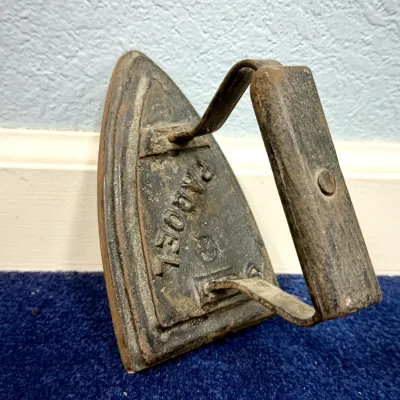 Sale Photo Thumbnail #50: Antique cast iron sad iron featuring raised "PAGOEL" lettering and a metal handle, showing heavy age-related patina.