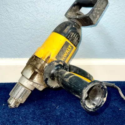 Sale Photo Thumbnail #610: DeWalt heavy-duty corded spade handle drill featuring a side auxiliary grip, showing visible signs of job site wear and surface dirt.