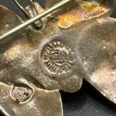 Sale Photo Thumbnail #189: Close-up view of the maker's mark and eagle stamp on the back of a vintage Mexican sterling silver brooch.