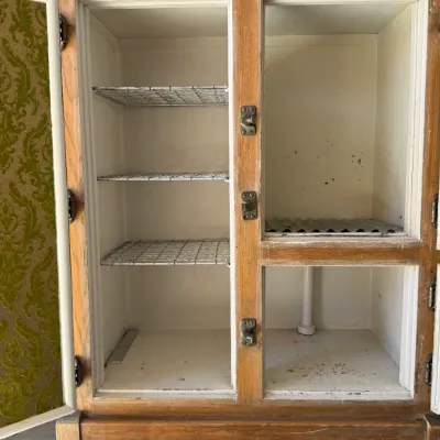Sale Photo Thumbnail #270: Vintage oak ice box cabinet featuring open doors lined with green flocked wallpaper, metal shelving, and original hardware.