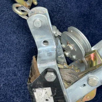 Sale Photo Thumbnail #659: Heavy-duty hand cable puller featuring steel construction, a pulley wheel, and a safety latch hook.