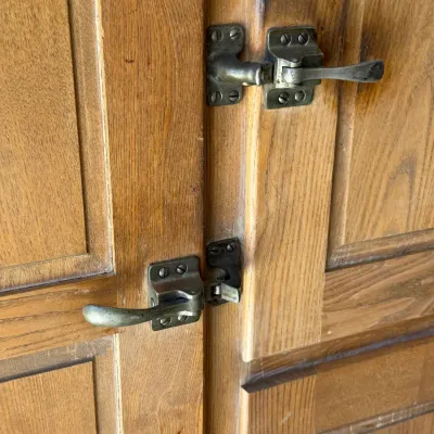 Sale Photo Thumbnail #266: Close-up of vintage metal latches on an oak icebox or wooden cabinet.