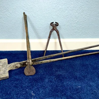 Sale Photo Thumbnail #573: Collection of antique blacksmith tools, including a large pair of forging tongs with a flattened paddle end and a pair of end-cutting nippers.