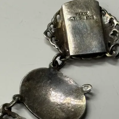 Sale Photo Thumbnail #168: Close-up view of a silver jewelry clasp stamped with "14K STERLING" hallmarks, showing light tarnish and surface wear.