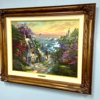 Sale Photo Thumbnail #822: Thomas Kinkade framed art print titled 'The Village Lighthouse', featuring an ornate wood and linen liner frame.