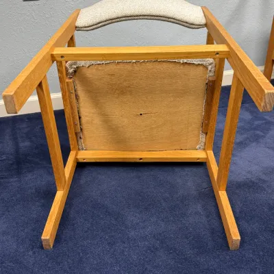 Sale Photo Thumbnail #698: Underside view of a Scandinavian modern oak arm chair featuring textured beige fabric upholstery and a solid wood frame.