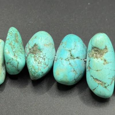 Sale Photo Thumbnail #352: Strand of polished turquoise nugget beads showing natural matrix variations.