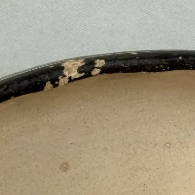 Sale Photo Thumbnail #133: Close-up detail of damage along the edge of a dark-rimmed furniture piece, showing wear and peeling finish.