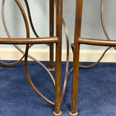 Sale Photo Thumbnail #308: Detail view of wrought iron or metal barstool frames featuring a bronzed finish and curved decorative scrollwork.