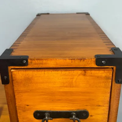 Sale Photo Thumbnail #213: Narrow wooden file cabinet or chest with campaign-style black metal corner brackets, a drop handle, and finger-jointed edge details.