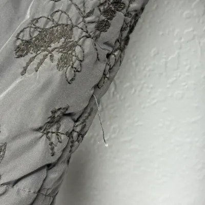 Sale Photo Thumbnail #900: Close-up detail of gray embroidered floral fabric showing a loose thread seam.