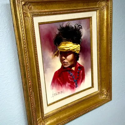 Sale Photo Thumbnail #138: Framed oil painting portrait of a Native American child with a yellow headband, signed by Goebel, housed in an ornate gilt wood frame.