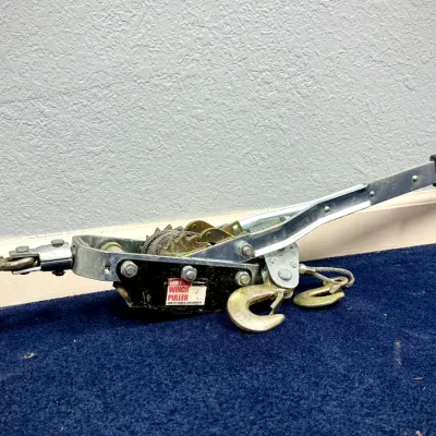 Sale Photo Thumbnail #59: Heavy-duty cable winch puller with ratchet handle and metal hooks, showing minor wear from light use.